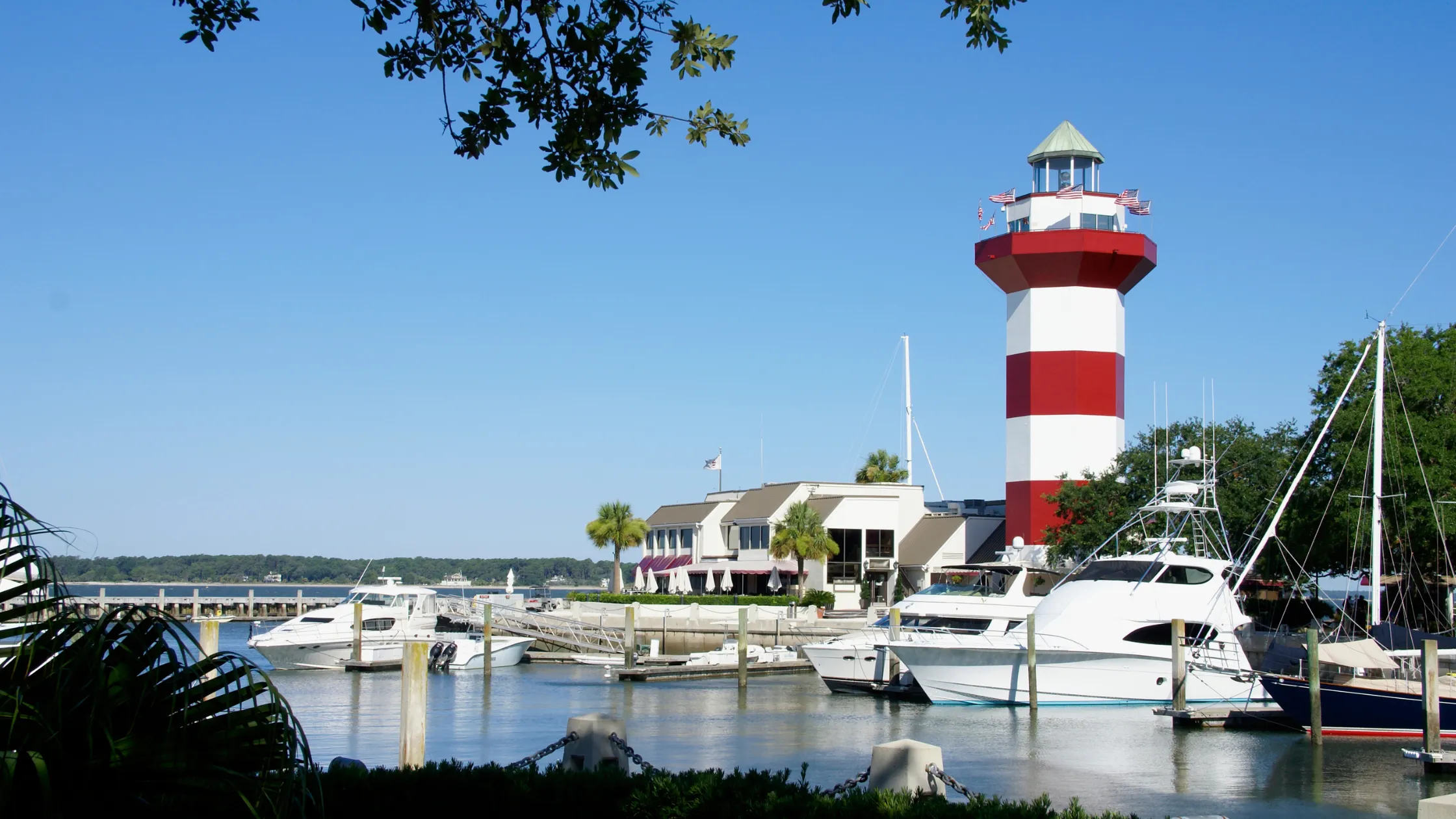 The iconic red and white striped lighthouse with yachts docked at the marina in Hilton Head.