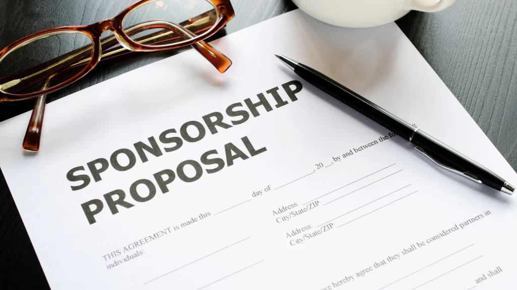 A close-up of a sponsorship proposal document with a pen and glasses on a desk.