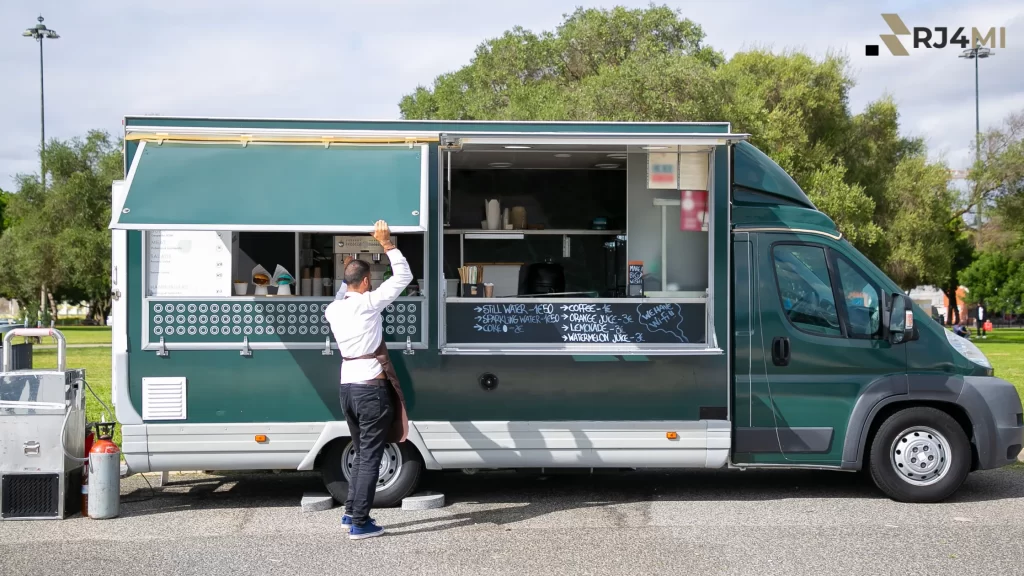 A sleek, green food truck offering a variety of beverages and snacks at an outdoor event.