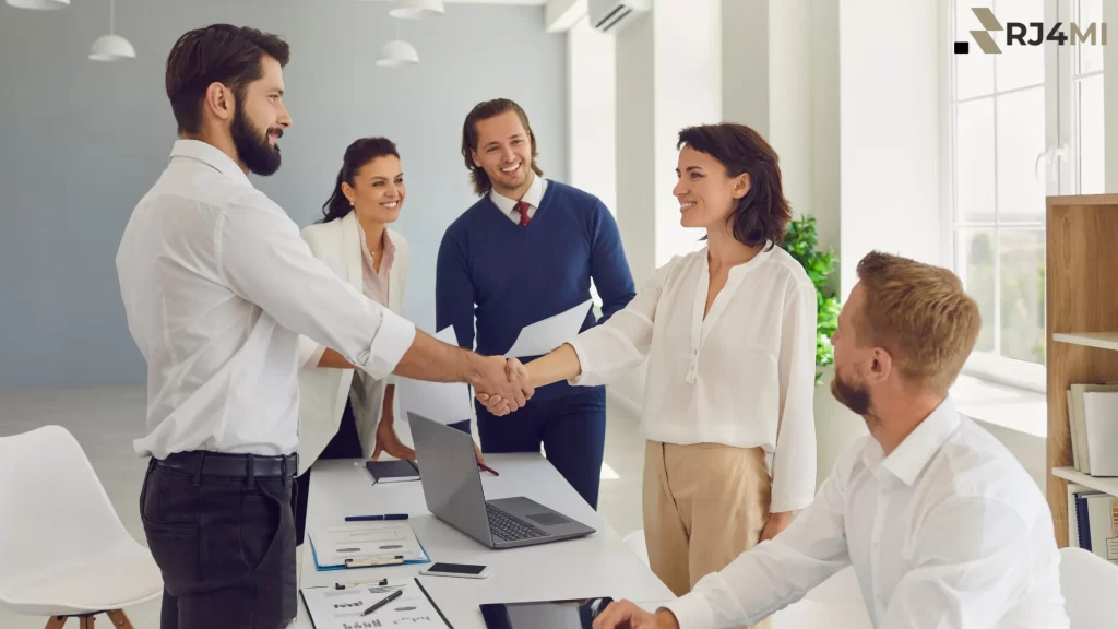 A confident business expert shakes hands with a client in a professional setting, showcasing self-trust and teamwork in business.