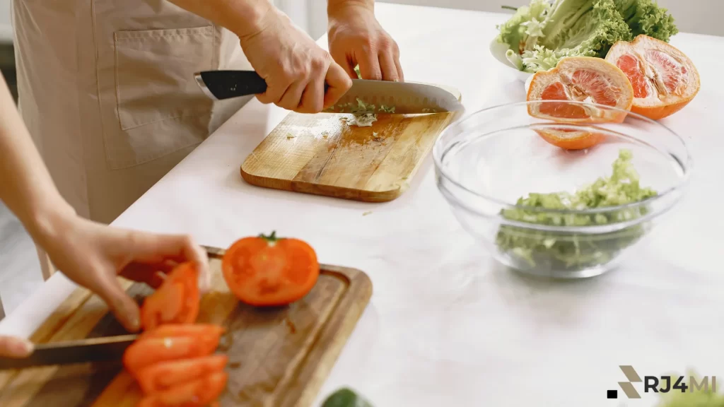 Hands chopping fresh vegetables like tomatoes and lettuce on wooden cutting boards, preparing a healthy meal.