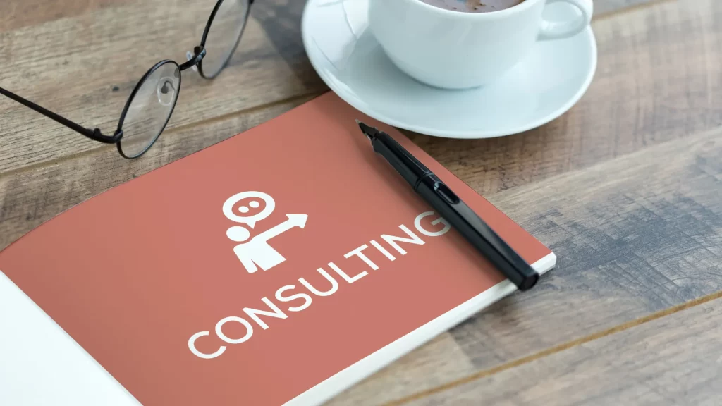 A notebook with the word 'Consulting' and a coffee cup, symbolizing educational consulting work.