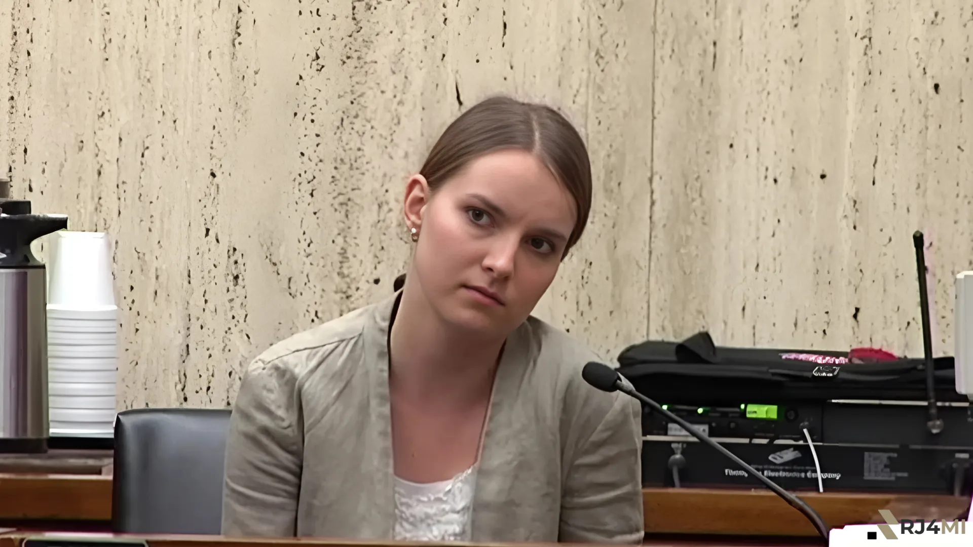 A woman at a courtroom witness stand, possibly related to events surrounding "what happened to Aina Dobilaite.